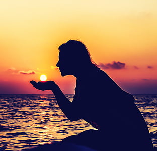 silhouette photography of woman kneeling on shore thumbnail