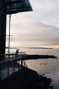 person on terrace near body of water thumbnail