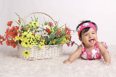baby lying beside flowers in white wicket basket thumbnail