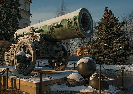 selective focus photo of cannon near pine tree under white clouds and blue sky thumbnail