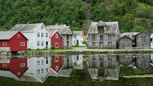 gray, white, and red concrete house reflecting on calm body of water at daytime thumbnail