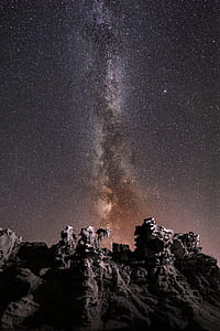 black rock formation under stars at night time thumbnail