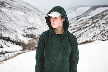 man in green hooded jacket walking on snow coated ground thumbnail