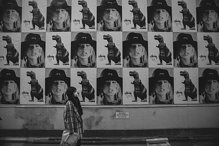 grayscale photography of woman looking at the poster on the wall thumbnail