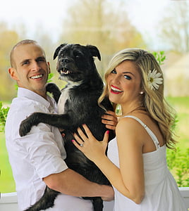 man and woman carrying dog looking on camera thumbnail