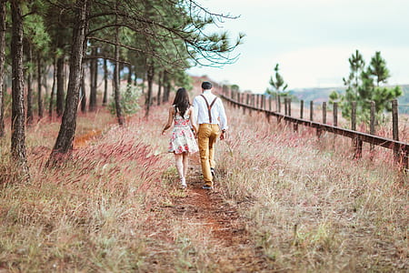 man wearing white dress shirt holding woman's hand walking on flower field thumbnail