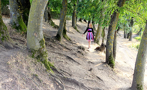 woman walking between trees thumbnail