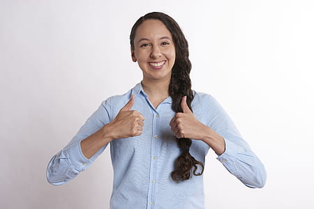 woman doing thumbs up sign near white wall thumbnail