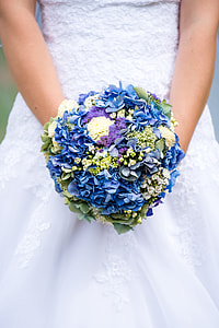 woman in white wedding dress holding blue flower bouquet thumbnail