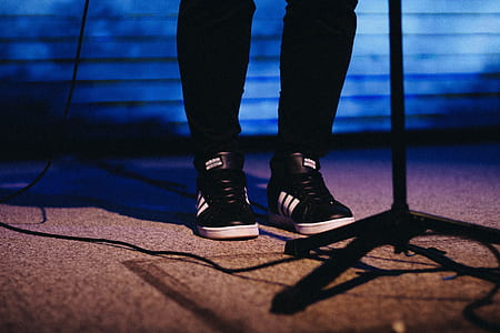 person wearing black adidas sneakers standing in front of black metal stand thumbnail