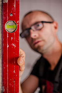 man wearing black framed eyeglass holding spirit level thumbnail