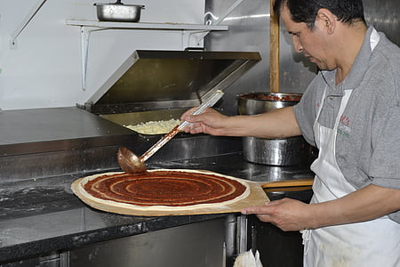 man putting sauce on pizza dough thumbnail