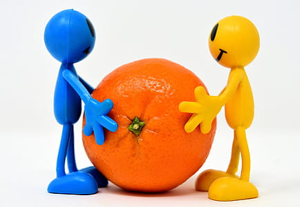 two blue and yellow silicone emoji mini figures holding orange fruit thumbnail