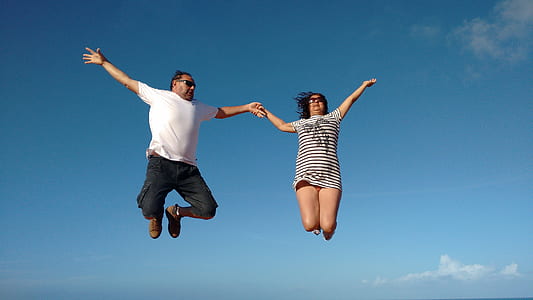 man and woman jumping under blue sky thumbnail