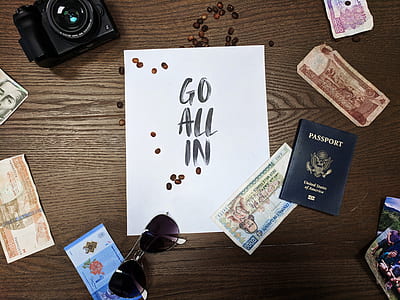 Go All in text on white paper sheet beside, banknotes, aviator-style sunglasses, and black bridge camera on brown wooden desk thumbnail