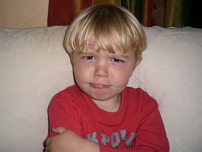 boy wearing red and gray crew-neck sweater behind beige pad thumbnail