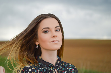 woman wearing black and blue floral top standing on green field thumbnail