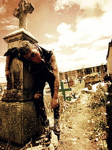 man wearing vest leaning on tomb thumbnail