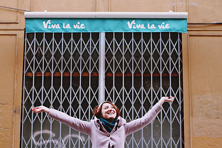 woman in gray coat smiling raising her hands thumbnail