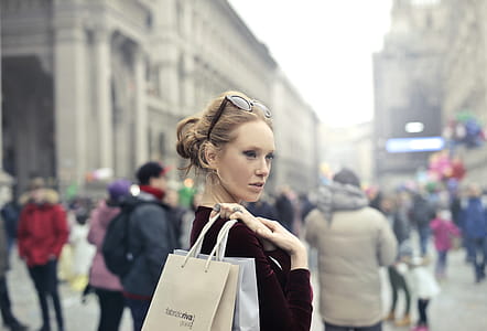 Woman Wearing Maroon Long-sleeved Top Carrying Brown and White Paper Bags in Selective Focus Photography thumbnail