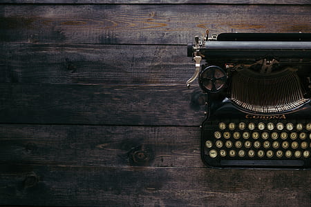 high-angle photo of black typewriter on brown wooden panel thumbnail