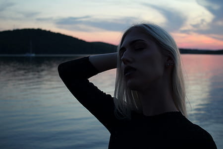 woman holding her head posing beside body of water thumbnail