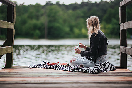 Blonde woman having a healthy snack at the wooden pier thumbnail