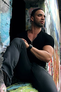 man wearing black shirt and pants sitting in window frame thumbnail