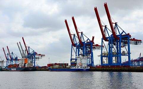 blue and red industrial cranes near body of water thumbnail