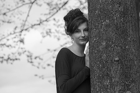 grayscale photography of woman hiding on tree trunk thumbnail