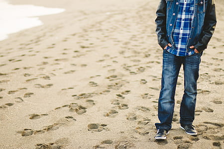 man wearing faded jeans standing on sand thumbnail