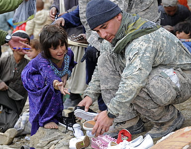 military man holding pair of shoes thumbnail