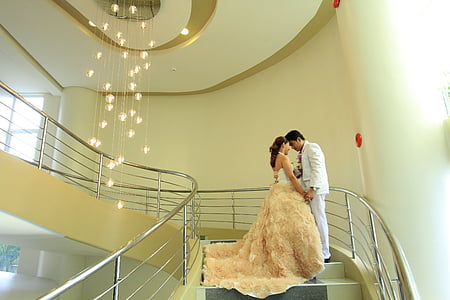 man and woman standing on staircase near chandelier thumbnail