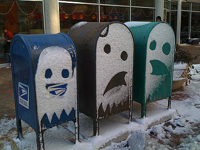 three assorted-color mailboxes with snow face arts during daytime thumbnail