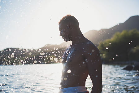 man standing on shallow body of water during daytime thumbnail