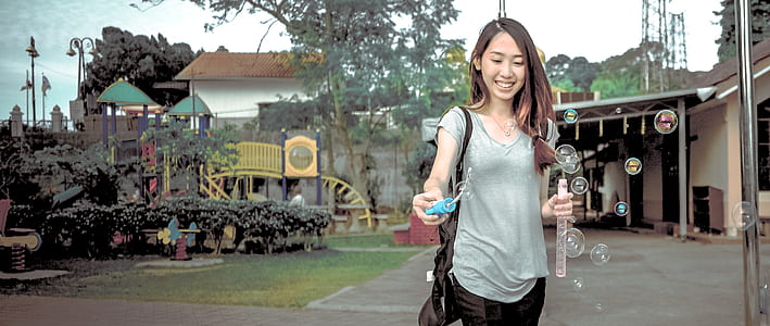 Woman Wearing Gray V Neck Cap Sleeve Top Making Bubbles thumbnail