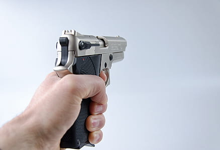 person holding black and gold semi-automatic pistol thumbnail