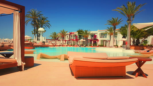 brown wooden bed beside swimming pool under blue sky thumbnail
