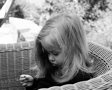 grayscale photo of girl sitting on rattan chair thumbnail