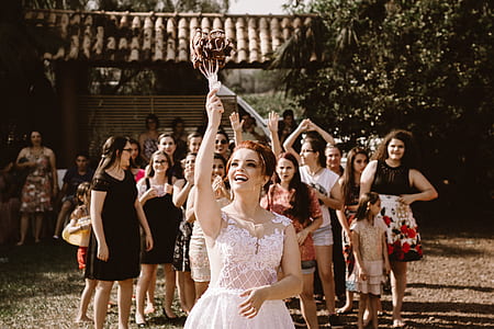 bride throwing bouquet of flowers on group of women on her back thumbnail