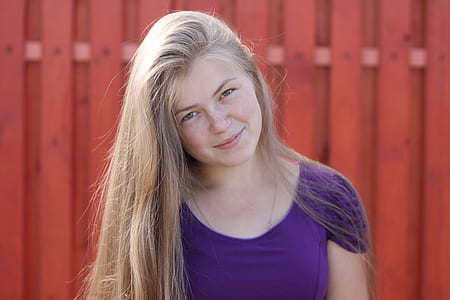 woman wearing purple scoop-neck shirt standing beside red wooden fence thumbnail