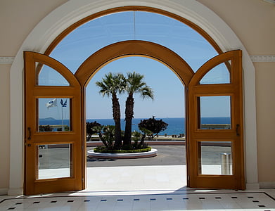 opened brown wooden and glass door near palm trees thumbnail