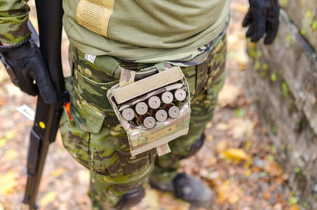 Person in Green Camouflage Print Pants Carrying Shotgun Shells thumbnail