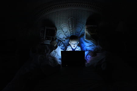 boy using laptop on bed near headboard thumbnail