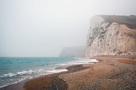photography of beach near foggy mountains thumbnail