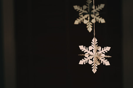 close view of white snowflake cut-out paper hanging on thin string thumbnail
