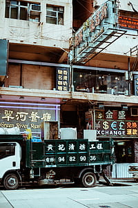 white and green truck parked beside building during daytime thumbnail