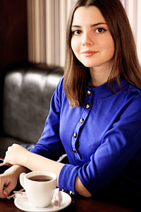 woman wearing blue button-up long-sleeved blouse in front of white ceramic mug with coffee thumbnail