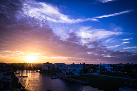 houses beside river under cloudy sky thumbnail