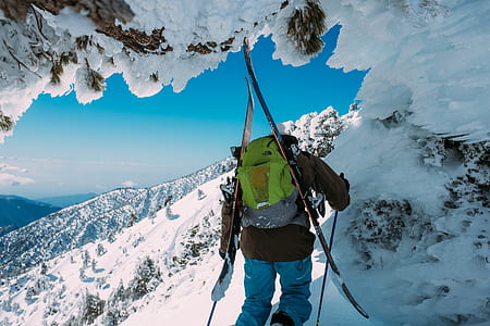 man carrying green backpack on snow-capped mountain thumbnail